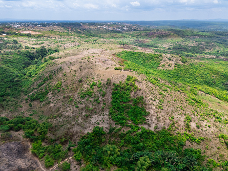 Aerial view of undulating hillsides showcasing a vibrant contrast of lush green foliage and sun baked lighter brown earth under a cloudy sky Ohafia Abia Nigeria. Aerial view of undulating hillsides showcasing a vibrant contrast of lush green foliage and sun baked lighter brown earth under a cloudy sky Ohafia Abia Nigeria.