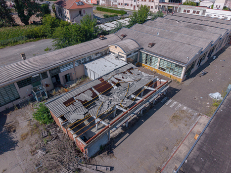 Aerial view of an abandoned industrial building with a partially collapsed roof and surrounding paved yard in Casale Monferrato Piedmont Italy. Aerial view of an abandoned industrial building with a partially collapsed roof and surrounding paved yard in Casale Monferrato Piedmont Italy.