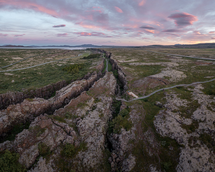 Aerial view of Thingvellir National Park featuring the tectonic rift valley with volcanic rock mossy terrain and walking paths under a sunset sky in Selfoss Blaskogabyggd Iceland. Aerial view of Thingvellir National Park featuring the tectonic rift valley with volcanic rock mossy terrain and walking paths under a sunset sky in Selfoss Blaskogabyggd Iceland.