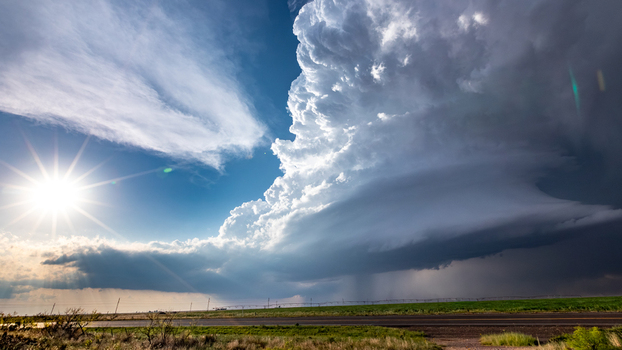 View of a massive supercell storm cloud with dramatic lighting and dark rain curtains over a rural landscape in Oklahoma City Oklahoma United States.