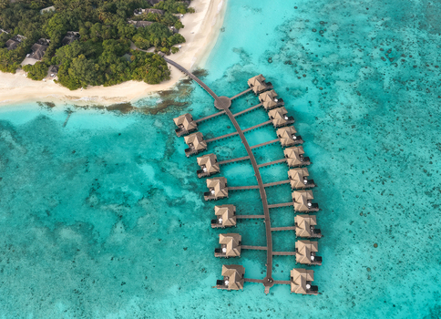 Aerial view of overwater bungalows arranged along a wooden pier over turquoise lagoon waters and coral reefs in Hoarafushi Haa Alif Atoll Maldives. Aerial view of overwater bungalows arranged along a wooden pier over turquoise lagoon waters and coral reefs in Hoarafushi Haa Alif Atoll Maldives.