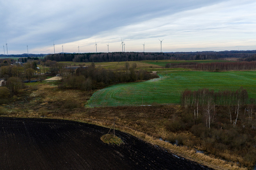 Aerial view of wind turbines on the horizon over green fields and dense forests under a cloudy sky in Nemencine Vilnius County Lithuania. Aerial view of wind turbines on the horizon over green fields and dense forests under a cloudy sky in Nemencine Vilnius County Lithuania.