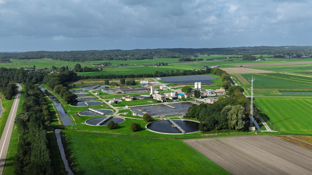 Aerial view of a wastewater treatment plant with circular settling tanks and rectangular aeration basins surrounded by green agricultural fields and trees in Warmenhuizen North Holland Netherlands. Aerial view of a wastewater treatment plant with circular settling tanks and rectangular aeration basins surrounded by green agricultural fields and trees in Warmenhuizen North Holland Netherlands.