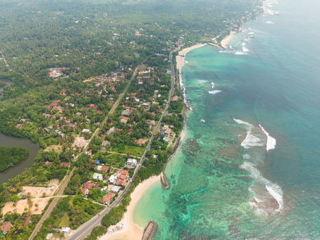 Aerial view of Devil s Rock surrounded by turquoise ocean waves sandy beaches and lush tropical vegetation along the coastline in Ahangama Southern Province Sri Lanka. Aerial view of Devil s Rock surrounded by turquoise ocean waves sandy beaches and lush tropical vegetation along the coastline in Ahangama Southern Province Sri Lanka.
