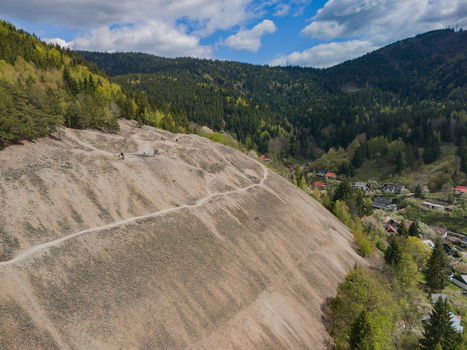 Aerial view of the historic mining mound and village surrounded by dense green forests and rolling hills under a cloudy sky Spania Dolina Banska Bystrica Region Slovakia.