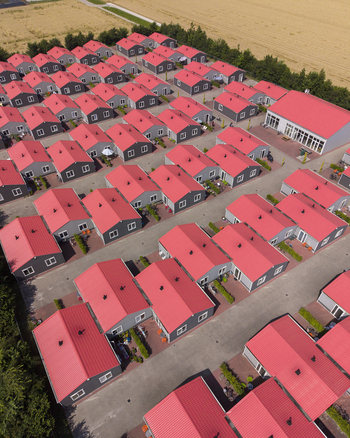 Aerial view of the prefabricated housing for migrant and seasonal workers featuring uniform grey buildings with red roofs arranged in an organized layout in Swifterbant Flevoland Netherlands. Aerial view of the prefabricated housing for migrant and seasonal workers featuring uniform grey buildings with red roofs arranged in an organized layout in Swifterbant Flevoland Netherlands.