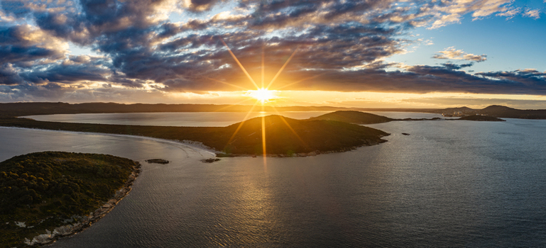 Aerial view of Torndirrup National Park at sunset with golden light reflecting on the water surrounding islands and dramatic clouds in Albany Western Australia Australia. Aerial view of Torndirrup National Park at sunset with golden light reflecting on the water surrounding islands and dramatic clouds in Albany Western Australia Australia.