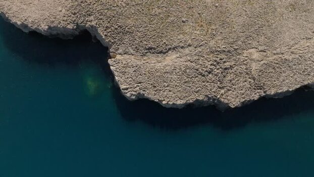Aerial view of the rocky cliffs and blue sea in Plemmirio Italy.