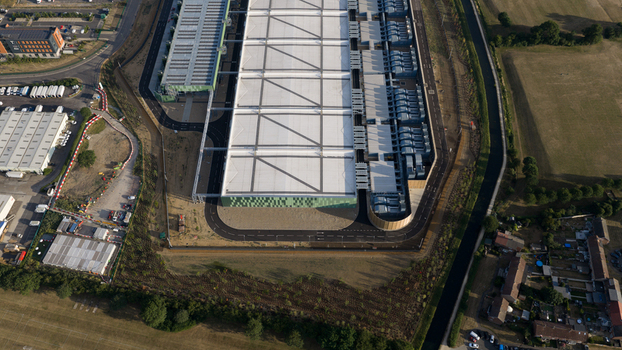 Aerial view of a large modern industrial warehouse facility with a white roof green facade and surrounding paved roads in Waltham Cross England United Kingdom.