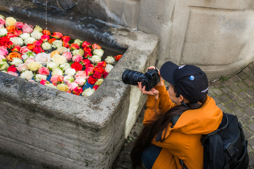 Zurich Switzerland 02 April 2023 View of a photographer capturing the vibrant spectacle of colorful roses floating serenely in the stone fountain s weathered basin. Zurich Switzerland 02 April 2023 View of a photographer capturing the vibrant spectacle of colorful roses floating serenely in the stone fountain s weathered basin.
