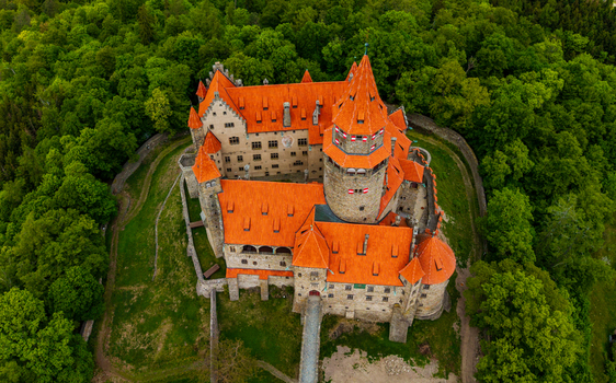 Aerial view of Bouzov Castle with its distinctive red tiled roofs and stone towers nestled within a lush green forest in Bouzov Olomoucky kraj Czechia. Aerial view of Bouzov Castle with its distinctive red tiled roofs and stone towers nestled within a lush green forest in Bouzov Olomoucky kraj Czechia.