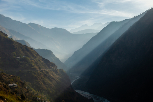View of sunbeams piercing through the mist in the deep Neelum Valley with a winding river and steep mountain slopes in Arang Kel Azad Kashmir Pakistan. View of sunbeams piercing through the mist in the deep Neelum Valley with a winding river and steep mountain slopes in Arang Kel Azad Kashmir Pakistan.