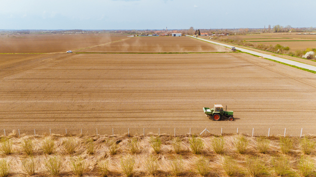 Aerial view of the tractor tilling the soil in the vast open field with the road to the farm in the distance Sremska Mitrovica Vojvodina Serbia. Aerial view of the tractor tilling the soil in the vast open field with the road to the farm in the distance Sremska Mitrovica Vojvodina Serbia.