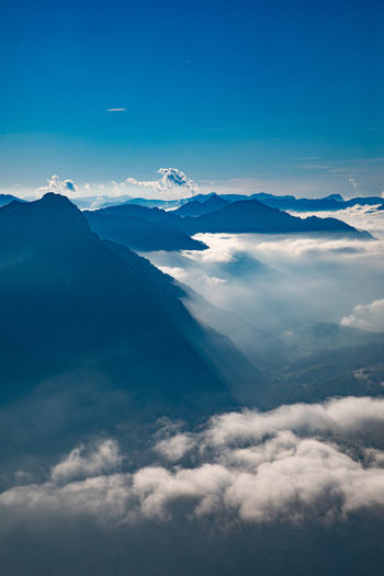 Aerial view of the Swiss Alps with dramatic mountain peaks rising above a sea of clouds under a clear blue sky in Airolo Ticino Switzerland. Aerial view of the Swiss Alps with dramatic mountain peaks rising above a sea of clouds under a clear blue sky in Airolo Ticino Switzerland.
