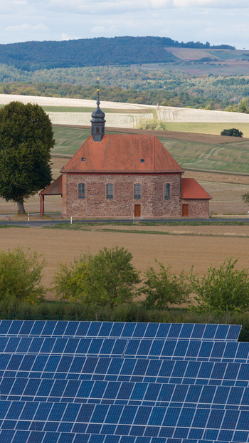 Aerial view of the historic Wendelinuskapelle surrounded by agricultural fields and a large solar panel array in the foreground in Dieburg Hessen Germany. Aerial view of the historic Wendelinuskapelle surrounded by agricultural fields and a large solar panel array in the foreground in Dieburg Hessen Germany.