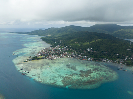 Aerial view of a vibrant village nestled amidst turquoise waters and lush greenery framed by distant mountains Karimunjawa Central Java Indonesia. Aerial view of a vibrant village nestled amidst turquoise waters and lush greenery framed by distant mountains Karimunjawa Central Java Indonesia.