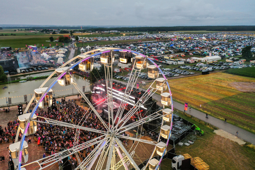 Herzogenaurach Germany 26 July 2025 Aerial view of the Open Beatz Festival featuring a large Ferris wheel crowded stages and vast camping areas under an overcast sky.