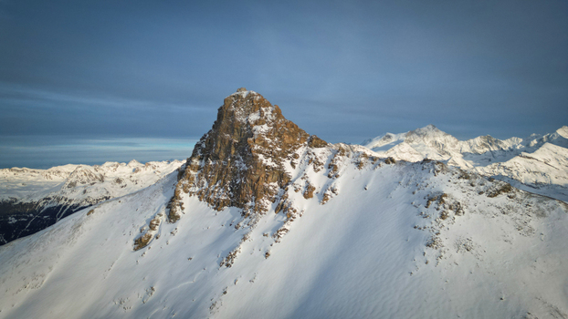 Aerial view of the majestic Becs des Bossons Peak where sunlight kisses the snow dusted summits creating a symphony of light and shadow Anniviers Valais Switzerland.