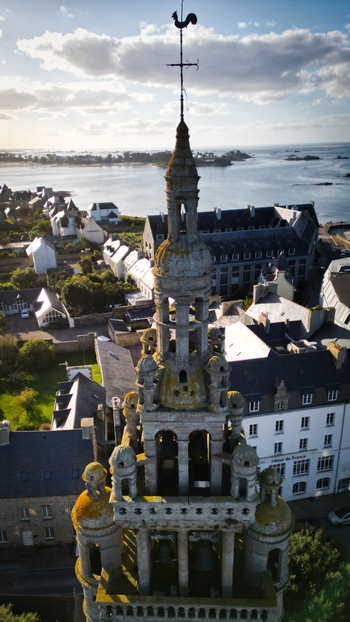 Aerial view of the ornate steeple adorned with a weather vane rises majestically against the backdrop of the sea Roscoff Bretagne France. Aerial view of the ornate steeple adorned with a weather vane rises majestically against the backdrop of the sea Roscoff Bretagne France.
