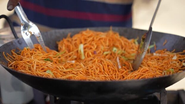 View of a street food vendor cooking noodles in a large wok Nepal. View of a street food vendor cooking noodles in a large wok Nepal.