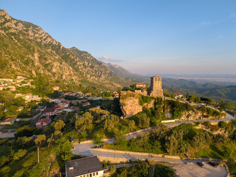 Aerial view of the historic Kruja Castle and its clock tower perched on a rocky hill against the Skanderbeg Mountains at sunset Kruje Durres County Albania.