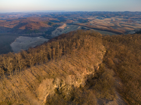 Aerial view of a rugged rocky ridge cloaked in leafless trees under the diffused light of a winter s day Cerova vrchovina Banska Bystrica Region Slovakia.