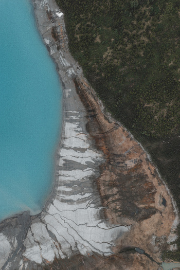 Aerial view of the glacial lake shoreline with turquoise water sediment patterns and dense forest in the Alaska Wilderness Eklutna Alaska United States. Aerial view of the glacial lake shoreline with turquoise water sediment patterns and dense forest in the Alaska Wilderness Eklutna Alaska United States.