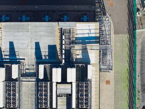 Aerial view of a data center roof featuring multiple industrial cooling fans ventilation units and metal infrastructure in the United Kingdom.