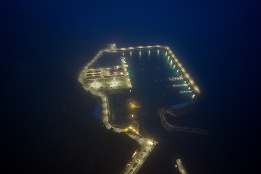 Aerial view of the illuminated harbor at night with glowing streetlights along the breakwater and boats docked in the dark water in Cudillero Asturias Spain. Aerial view of the illuminated harbor at night with glowing streetlights along the breakwater and boats docked in the dark water in Cudillero Asturias Spain.