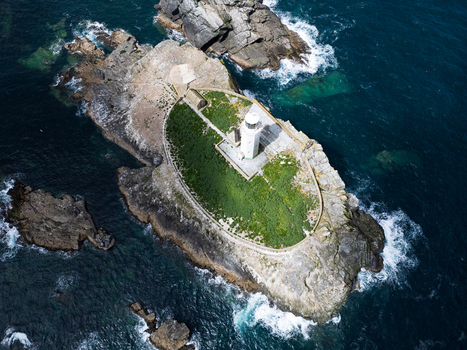 Aerial view of Godrevy Lighthouse on a rocky island surrounded by the dark blue waters of the Atlantic Ocean in Gwithian England United Kingdom. Aerial view of Godrevy Lighthouse on a rocky island surrounded by the dark blue waters of the Atlantic Ocean in Gwithian England United Kingdom.