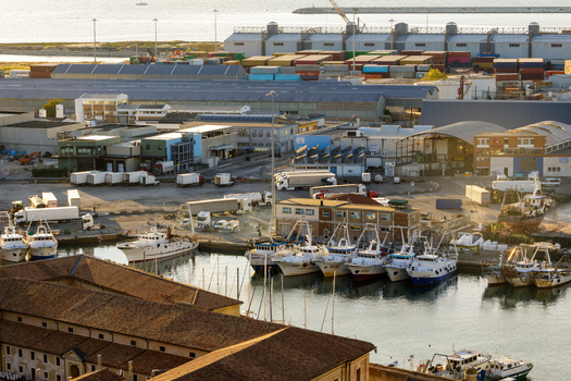 Aerial view of Ancona Port with fishing boats docked in the harbor industrial warehouses and shipping containers under warm sunlight in Ancona Marche Italy. Aerial view of Ancona Port with fishing boats docked in the harbor industrial warehouses and shipping containers under warm sunlight in Ancona Marche Italy.