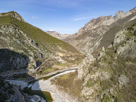 Aerial view of Lume i Kirit flowing through the rugged mountain landscape with rocky cliffs green slopes and a winding road in Shkoder Qarku i Shkodres Albania. Aerial view of Lume i Kirit flowing through the rugged mountain landscape with rocky cliffs green slopes and a winding road in Shkoder Qarku i Shkodres Albania.