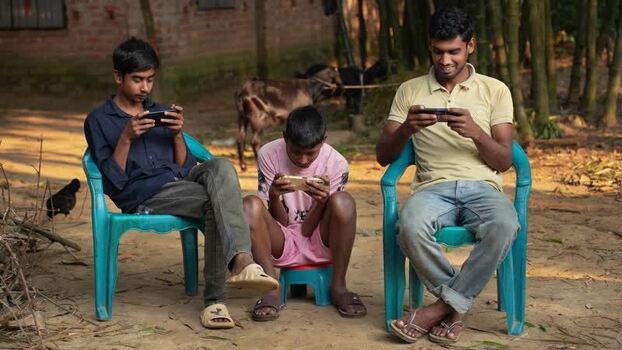 View of young men using smartphones in a rural village Bangladesh. View of young men using smartphones in a rural village Bangladesh.