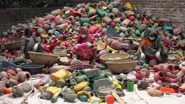 View of women sorting through a large pile of plastic waste Bangladesh. View of women sorting through a large pile of plastic waste Bangladesh.