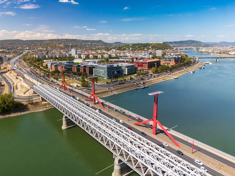 Aerial view of Rakoczi Bridge over the Danube in Budapest Hungary with the BME university campus city skyline roads boats and Buda Hills under a cloudy summer sky. Aerial view of Rakoczi Bridge over the Danube in Budapest Hungary with the BME university campus city skyline roads boats and Buda Hills under a cloudy summer sky.