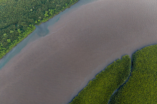 Aerial view of a winding river flowing through dense mangrove forests in the Niger Delta Opobo Town Rivers Nigeria. Aerial view of a winding river flowing through dense mangrove forests in the Niger Delta Opobo Town Rivers Nigeria.
