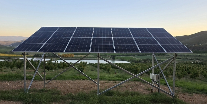 View of a solar panel array installed in a rural orchard with rolling hills in the background during golden hour in Hoeko Western Cape South Africa. View of a solar panel array installed in a rural orchard with rolling hills in the background during golden hour in Hoeko Western Cape South Africa.
