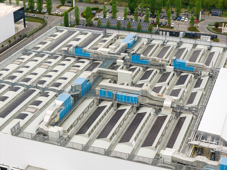 Aerial view of a large industrial building rooftop featuring ventilation units skylights and solar panels in San Giovanni Valdarno Tuscany Italy.