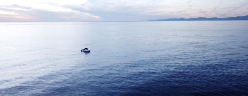 Aerial view of a small boat floating on the calm blue ocean waters off the coast of Los Angeles California United States.