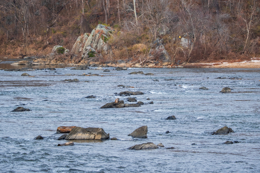 View of the Potomac River flowing over rocks reflecting the sky with a rocky outcropping in the background Scott s Run Virginia United States. View of the Potomac River flowing over rocks reflecting the sky with a rocky outcropping in the background Scott s Run Virginia United States.