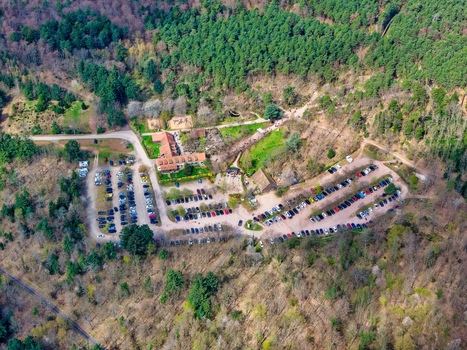 Aerial view of dense woodland surrounding a large parking area filled with cars near buildings Kintzheim Grand Est France.