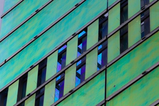View of the building s facade displaying vibrant green panels complemented by the cool dark reflections of the windows La Defense Flevoland Netherlands. View of the building s facade displaying vibrant green panels complemented by the cool dark reflections of the windows La Defense Flevoland Netherlands.