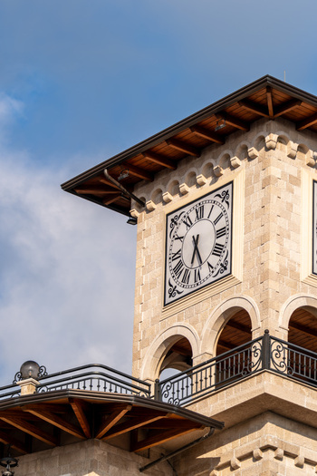 View of the historic stone clock tower with its Roman numeral face and arched windows under a blue sky in Kruje Durres County Albania.