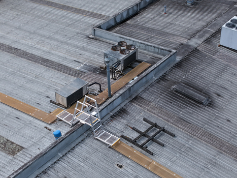 Aerial view of an industrial rooftop featuring metal surfaces HVAC units a maintenance ladder and walkways in Melbourne VIC Australia.