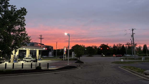 Loveland United States 18 April 2026 View of a gas station under a vibrant pink sunset sky with street lights and power lines.