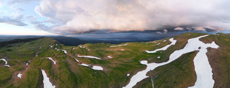 Aerial view of Le Colomby de Gex mountain ridge with patches of snow and dramatic storm clouds over the valley in Echenevex Auvergne Rhone Alpes France. Aerial view of Le Colomby de Gex mountain ridge with patches of snow and dramatic storm clouds over the valley in Echenevex Auvergne Rhone Alpes France.