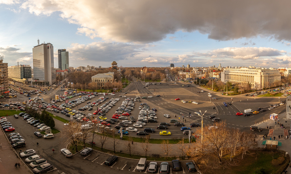 View of the busy University Square in Bucharest with a large parking area surrounding historic and modern buildings and traffic in Bucharest Bucharest Romania. View of the busy University Square in Bucharest with a large parking area surrounding historic and modern buildings and traffic in Bucharest Bucharest Romania.