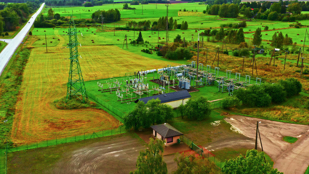 Aerial view of an electrical substation situated in a rural landscape with green fields power lines and a small building in Latvia. Aerial view of an electrical substation situated in a rural landscape with green fields power lines and a small building in Latvia.