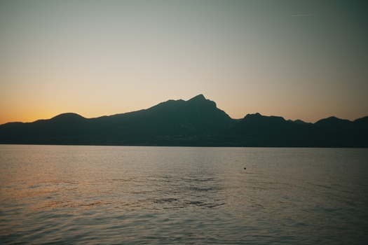 View of Lake Garda with the silhouette of mountains against a sunset sky in Italy. View of Lake Garda with the silhouette of mountains against a sunset sky in Italy.
