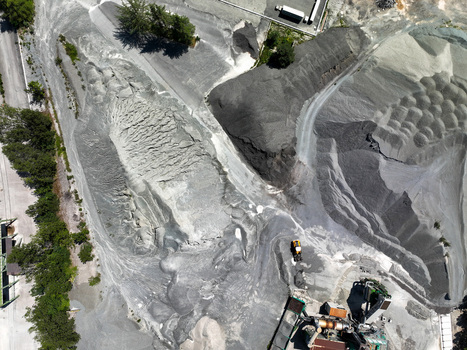 Aerial view of an industrial quarry with large piles of grey gravel heavy machinery and surrounding green trees Caprie Piedmont Italy. Aerial view of an industrial quarry with large piles of grey gravel heavy machinery and surrounding green trees Caprie Piedmont Italy.